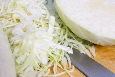 Tahtanın üzerinde, bıçağın yanında doğranmış taze lahana.