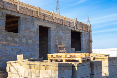Cüruf briketlerinden bir ev inşa etmek. Binanın ilk katı tamamlanmış. İnşaat için beton bloklar paletlerin üzerinde.