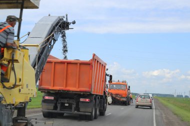 Kamyonlar yol onarımı, temiz eski asfalt üzerinde çalışıyor.