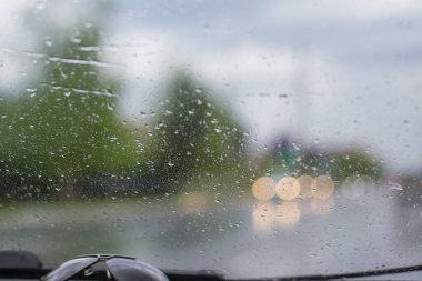 Islak ön camdan şehrin sokakları görünür, izole edilmiş trafik modu.