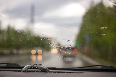Araba yağmurda yolda gidiyor, ıslak cam.