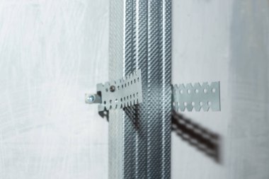 Alçıpan monte etmek için yan gri duvara metal bir profil monte edilir. İnşaat işleri ve ev tadilatı.