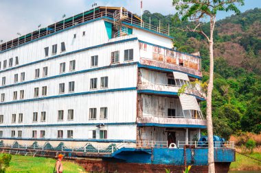 Koh Chang, Tayland-01.17.2020: Adada terk edilmiş bir otel - deniz kıyısında eski, paslı bir gemi, bir turist ona bakıyor