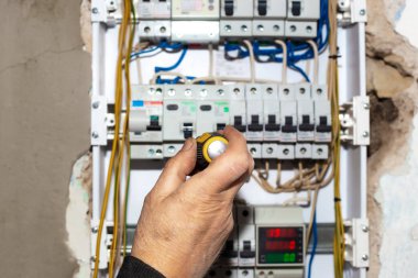 Elektrik santrali mi? Erkek bir elektrikçi evin duvarına elektriği kontrol etmek için çok işlevli bir kalkan yerleştiriyor..