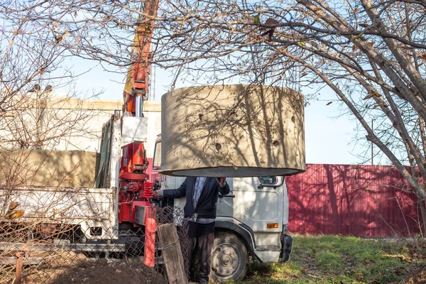 装卸工为建造化粪池而将直径1 5米的混凝土环卸到一个挖出的孔中 在村里安装下水道排水渠 — 图库照片