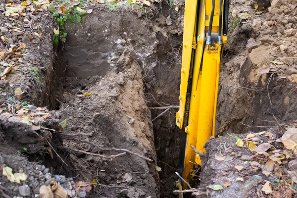 The excavator digs a hole for a septic tank. Working the machine with the ground.