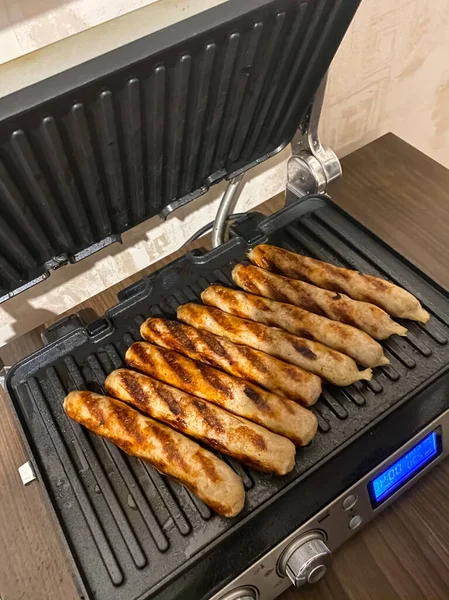Meat sausages are grilled on the electric grill. Delicious hearty food.