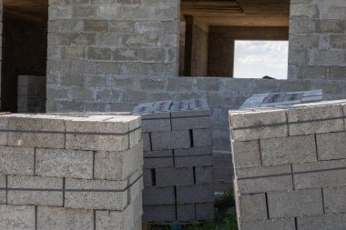 Cüruf briketlerinden yapılmış özel bir ev. İnşaat alanındaki paletlerin üzerindeki gri bloklar.