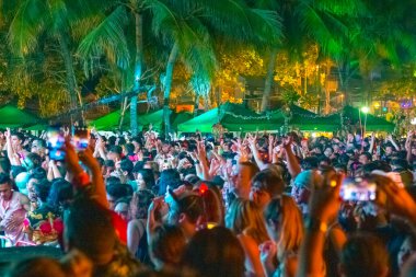 Phuket, Tayland-12.31.2018: Tropiklerdeki plajda gece yarısı dans eden gençlerden oluşan bir kalabalık bulanık bir zemin oluşturdu.