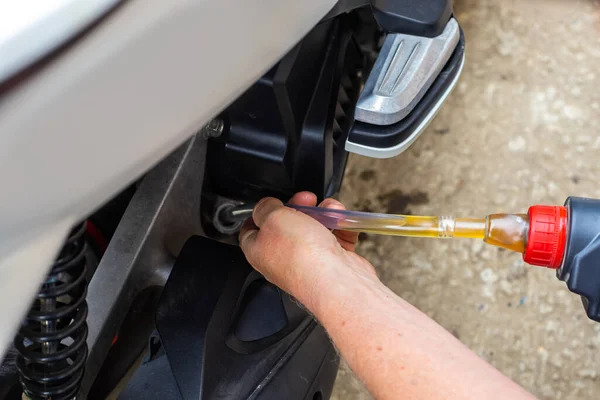 Repair and maintenance of a motorcycle. Oil change. The car mechanic pours oil into the engine through a rubber hose.