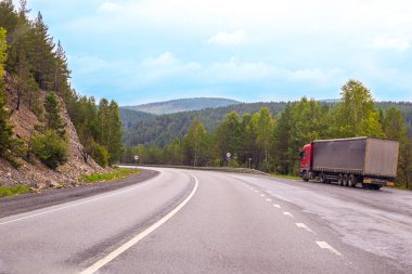 Urallar ve ormanların dağları arasında yol kenarında duran büyük bir minibüs malları taşıyor.