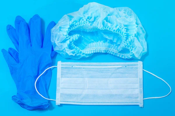 personal protective equipment - medical mask, hat, rubber gloves on a blue background, medical protection against viruses