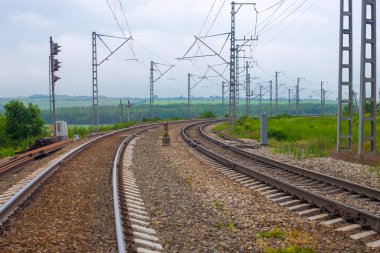 Yazın doğanın arka planında bir dönüşle demiryolu rayları. Seyahat ve turizm yolu.