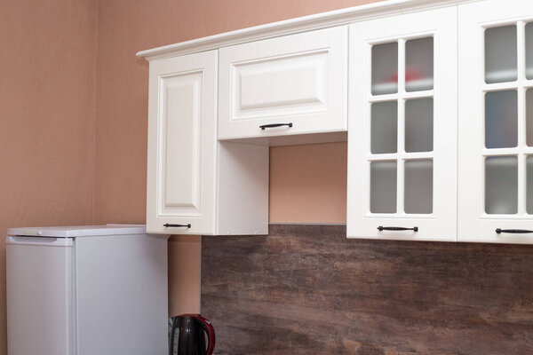 Kitchen interier. White wooden facade of a kitchen unit with household appliances.