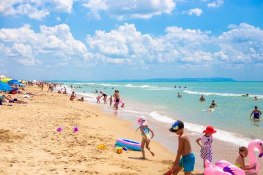 Anapa, Rusya-07.07.2021: Suda ve kıyıda bir grup turist eğleniyor ve eğleniyor. Güneşli bir günde Karadeniz kıyısında yaz tatili. İyi tatiller..