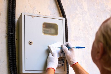 Elektrik sayacının transferi. Bir adam kilovatların sayısını yazar..