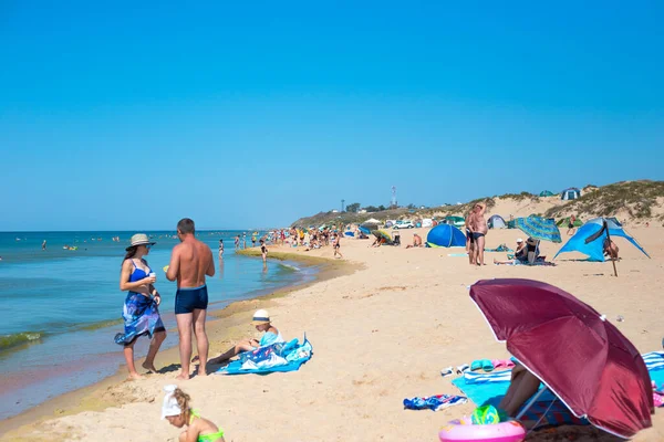 Los turistas nadan y toman el sol en la playa de arena de la costa del Mar Negro. Viajes y turismo. Vacaciones de verano y fin de semana —  Fotos de Stock