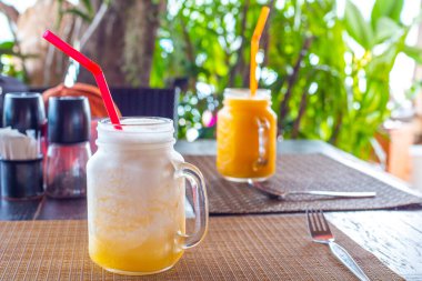 Cold smoothie made from mango and pineapple fruits on the table in a cafe. Rest in tropical countries, gastronomic tourism