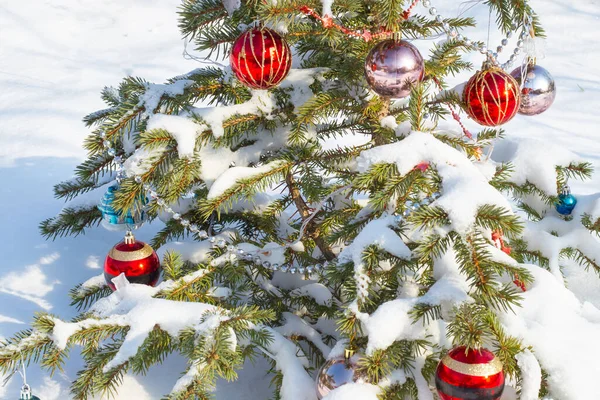 雪の中でおもちゃやビーズで飾られた緑のお祝いの小さなクリスマスツリー — ストック写真