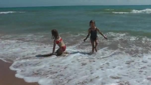 Çocuklar denizin dalgalarında oynarlar ve eğlenirler. Mutlu yaz, dinlenme ve iyileşme. — Stok video