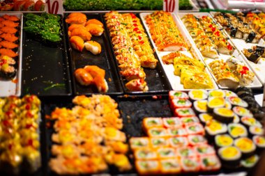 Suşi, arka planda bulanık bir şekilde bir markette bir tepside yuvarlanıyor.