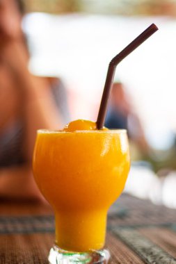 Sarı mango masanın üzerinde pipetle bardakta sallanıyor.