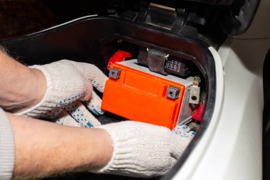 Motosiklet aküsünü değiştiriyorum. Araba servisindeki bir tamirci pili şarj etmek ya da değiştirmek için motosikletten çıkarır.