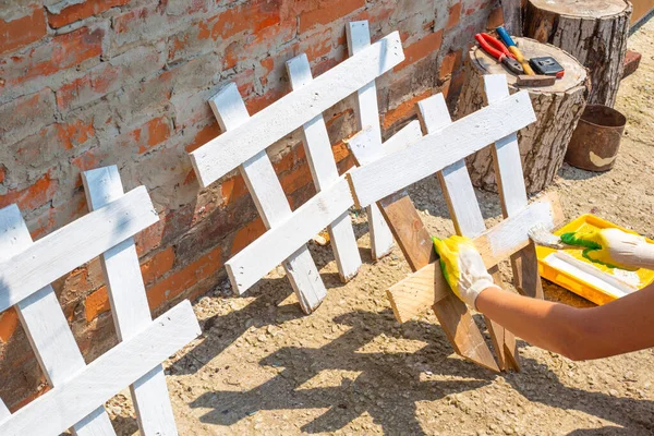 한 여자는 울타리를칠 하여 화단을 만듭니다. 정원에 울타리를 만들고 페인트칠을 하는 모습 — 스톡 사진