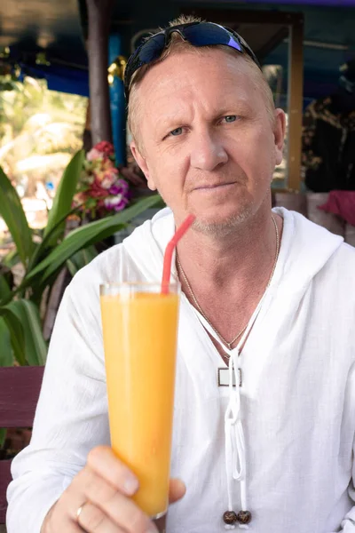 stock image mature european man sitting in cafe with mango cocktail