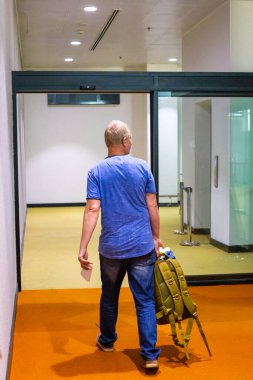 Havaalanında sırt çantalı bir adam, dikiz aynasından.