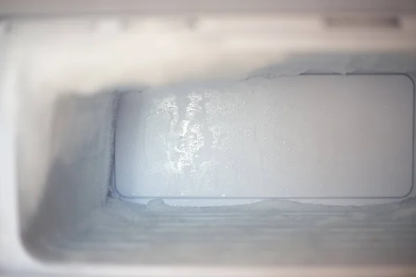 Frozen fridge freezer with ice. Household appliances care.