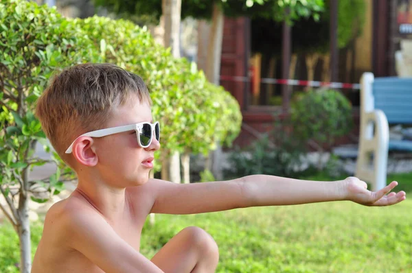 Ragazzino Occhiali Sole Seduto Sull Erba Con Braccio Teso — Foto Stock