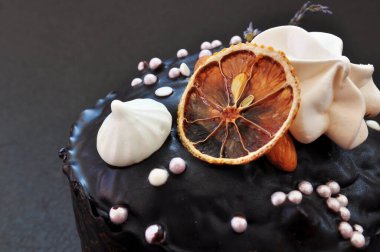 Siyah çikolatalı, fındıklı ve koyu arkaplanlı bir dilim limonlu Paskalya pastası.