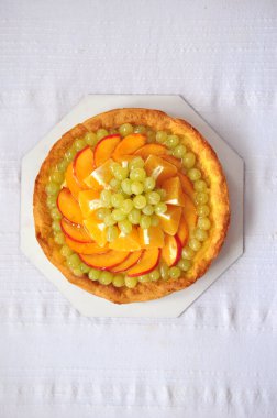 Yuvarlak meyveli turtanın beyaz masa örtüsü üzerinde üst görünümü, metnin için boş alan