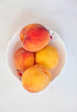 Lezzetli şeftaliler beyaz masa örtüsüne kapanıyor.