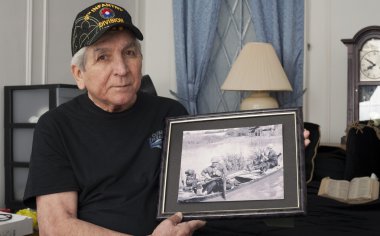 Vietnam war veteran holds an old war photo of himself. clipart