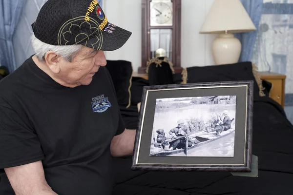 Veterano de la guerra de Vietnam mira la vieja foto de guerra de sí mismo . — Foto de Stock