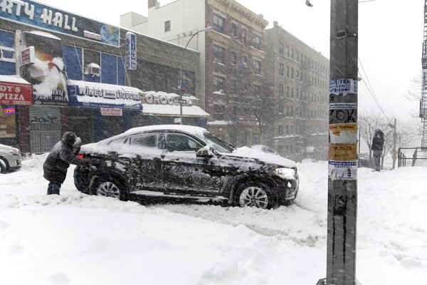 BRONX, NEW YORK - JANUARY 23: Man pushes stuck auto on Anderson Avenue street during Blizzard storm Jonas. Taken January 23, 2016, in the Bronx, New York.