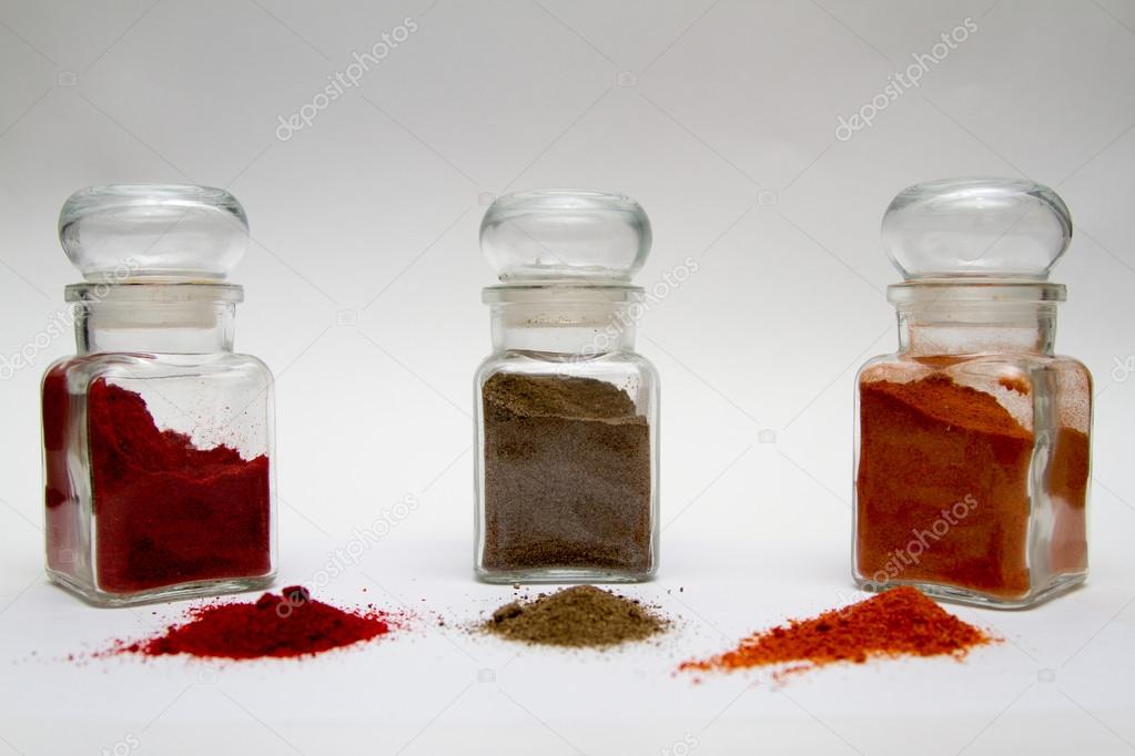 glass spice jars with different kinds of pepper