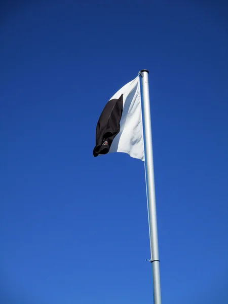 Bandeira branca e preta voando e — Fotografia de Stock