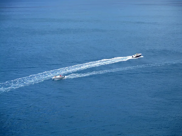 speed boats that leave a white strip in the blue sea b