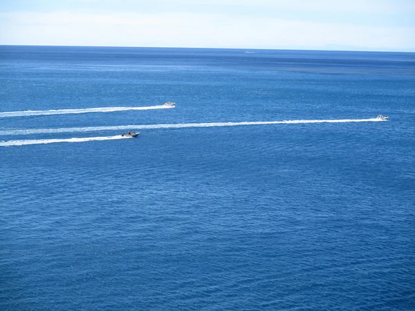 Speed boats that leave a white strip in the blue sea a — Stock Photo, Image
