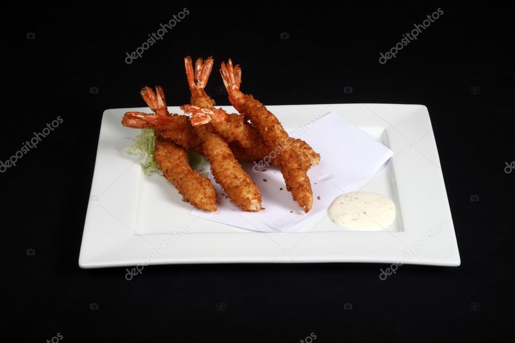 breaded prawns with vegetables and sauce in white plate