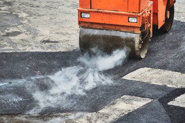 Yol silindirleri sıcak asfalt seriyor.