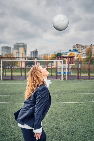 woman soccer player in an office suit stuffs the ball with her head. concept