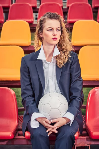 portrait of a beautiful woman soccer cheerleader in the stands of a stadium with a ball