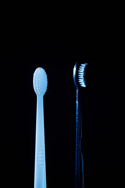 Twee Tandenborstels Blauwe Gloed Een Donkere Achtergrond — Stockfoto