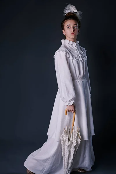 Beyaz elbiseli genç bir kızın eski moda bir portresi. Stüdyo. koyu arkaplan
