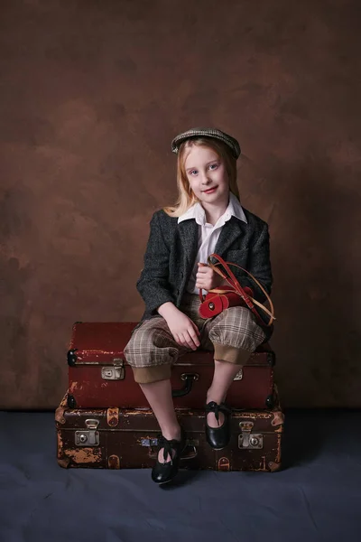 retro portrait of a little girl in a jacket with a leather camera case. studio. brown background