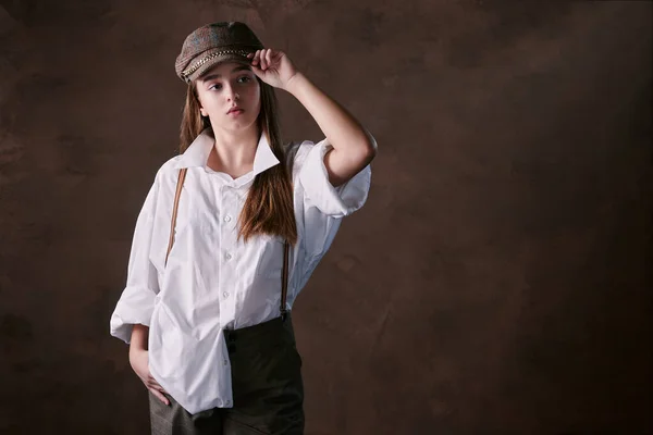 Şapkalı Vizörlü Beyaz Gömlekli Pantolonlu Bir Kız Stüdyo Kahverengi Arka — Stok fotoğraf